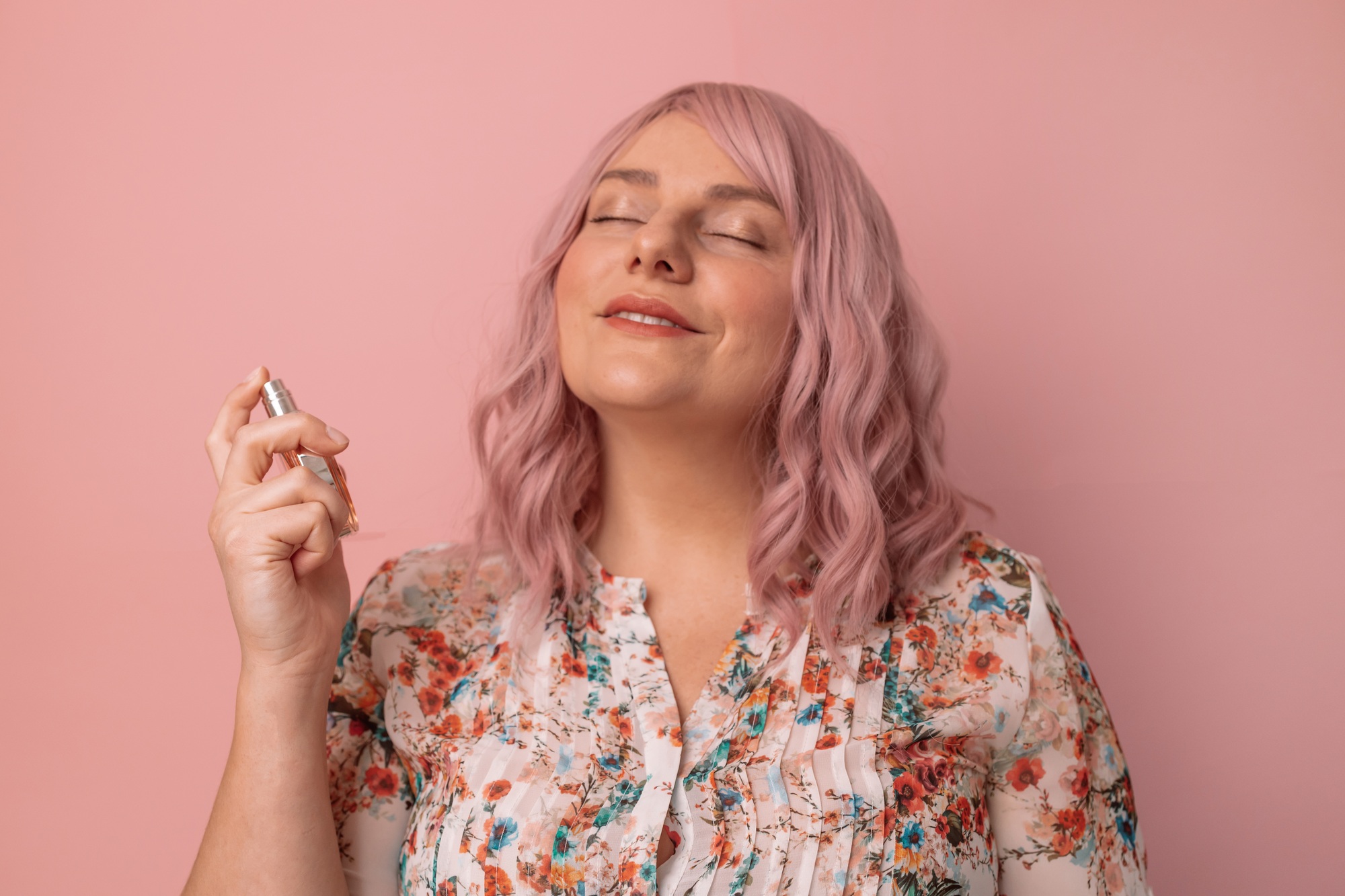 female with bottle of perfume and applying it. Beautiful girl using perfume